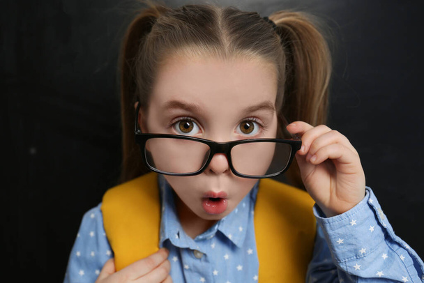 Cute child wearing glasses near chalkboard, closeup. First time at school - 写真・画像