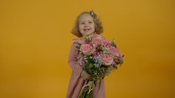 Ευτυχισμένο σγουρό παιδί κρατώντας μπουκέτο και αγγίζοντας λουλούδια - Πλάνα, βίντεο
