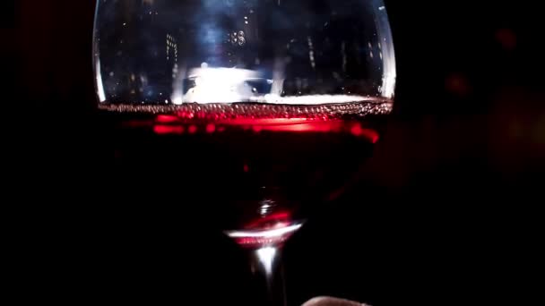 Rázza a vörösbort kézzel. Készletfelvétel. Közelről egy sommelier remeg borosüveg a kezében vörösbor a kezében egy sötét háttér - Felvétel, videó