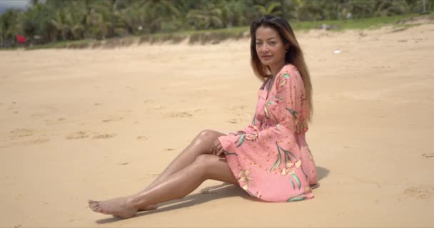 裸足の民族の女性がビーチに座っている - 映像、動画
