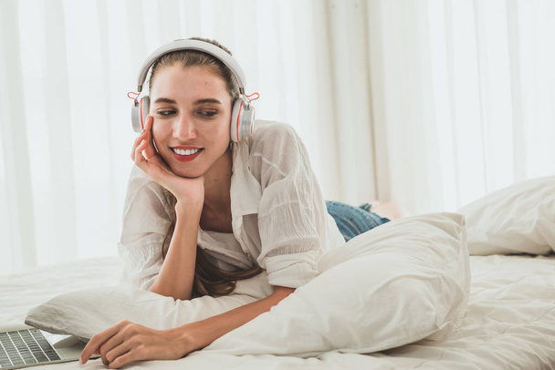 Beautiful young woman listening to music in headphones at home - 写真・画像