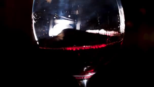 手で赤ワイングラスを振る。ストック映像だ。ソムリエのクローズアップは、暗い背景に彼の手の中に赤ワインとワイングラスを振る - 映像、動画