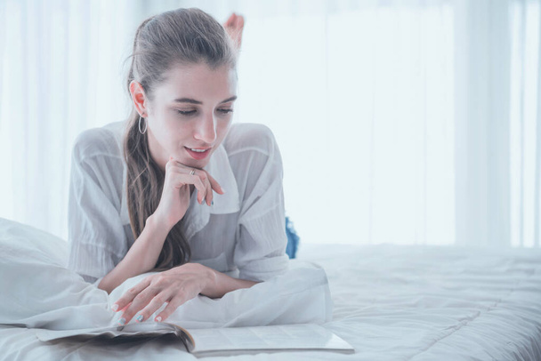 Giovane donna che si diverte a leggere un libro mentre si sdraia sul letto a casa
. - Foto, immagini