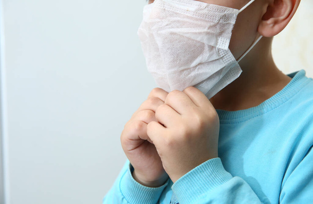 Kids wearing her mask is not comfortable, she has headache. Sick Child wearing surgical mask coughing . Kids wear health masks to prevent germs and dust . Protection against corona virus - Фото, зображення
