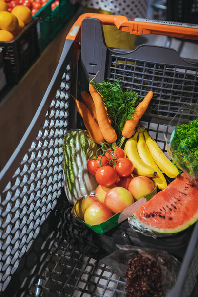 view of shopping cart full of vegetables and fruits grocery store - Foto, imagen