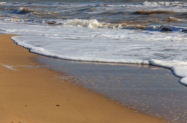 Eine sanfte Meereswelle rollt auf den Sand des Strandes. Meereslandwellen an der Küste - Foto, Bild