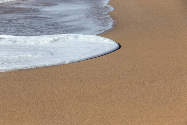 Una suave ola marina rueda sobre la arena de la playa. Ondas marinas en la costa
 - Foto, Imagen