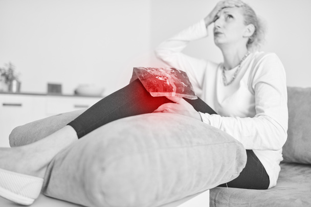 Поранена жінка тримає крижаний пакет / мішок для охолодження колінного болю
. - Фото, зображення
