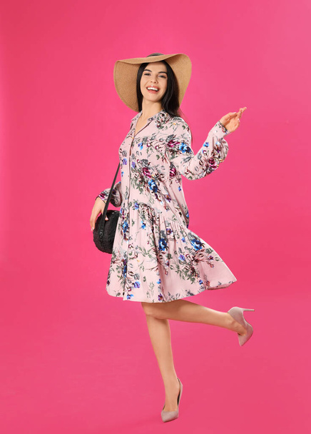 Young woman wearing floral print dress and straw hat on pink background - Fotografie, Obrázek
