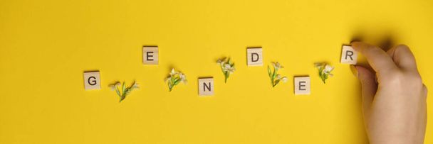 Género de palabras representado por el uso de bloques de madera y flores sobre fondo amarillo colorido
. - Foto, Imagen