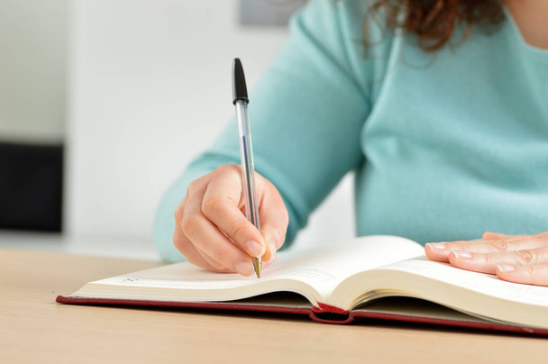 Close up of woman hand writing in an agenda at home - Фото, зображення