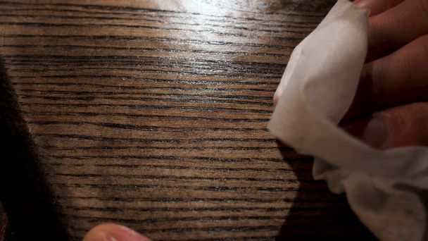 Mannelijke hand die houtverzorgingsproducten aanbrengt op een houten bord met witte doek. Voorraadbeelden. Sluiten van houten paneel olieverf proces. - Foto, afbeelding
