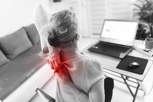 Mujer trabajando en una computadora portátil y teniendo dolor de manos, espalda, columna vertebral
. - Foto, Imagen