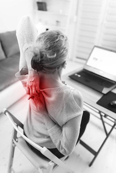 Mujer trabajando en una computadora portátil y teniendo dolor de manos, espalda, columna vertebral
. - Foto, Imagen