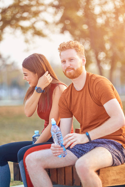 Modern couple making pause in an urban park during jogging / exercise. - Photo, Image