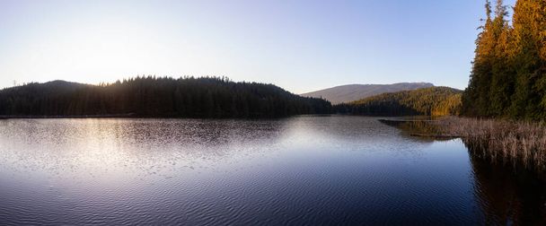Beautiful and Vibrant panoramic view of a lake surounded by Canadian Mountain Landscape during sunset. Taken in White Pine Beach, Port Moody, Vancouver, British Columbia, Canada. Panorama - Foto, Imagen