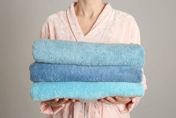 Woman holding fresh towels on grey background, closeup - Photo, image