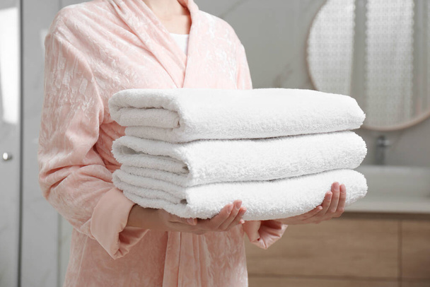 Woman holding fresh towels in bathroom, closeup - Foto, Bild