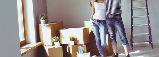 Happy young couple unpacking or packing boxes and moving into a new home - Фото, зображення
