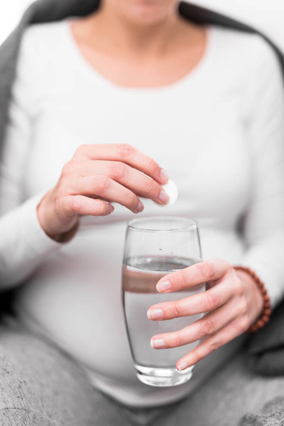 Pregnant woman taking vitamin tablet in a glass of water. - Foto, immagini