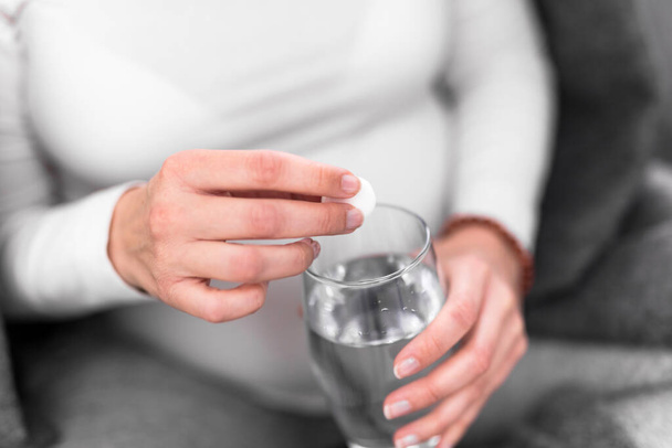 妊娠中の女性はビタミン錠をコップ一杯の水で飲んで. - 写真・画像