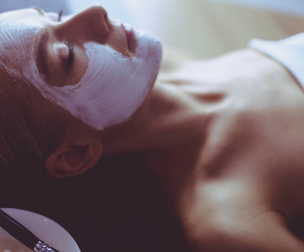 Máscara de rosto.Menina bonita no spa, mulher cosmetician aplicando máscara facial
. - Foto, Imagem