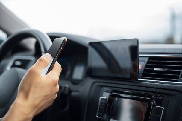 Close-up of driver hand holding smartphone inside car. - Photo, Image