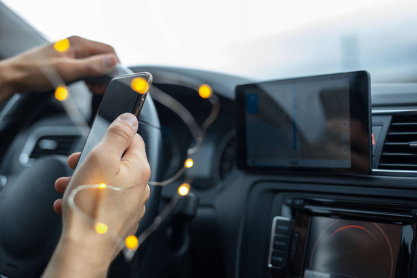 Close-up van de bestuurder hand holding smartphone in de auto. - Foto, afbeelding