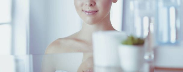 Young woman in bathrobe looking in bathroom mirror - Φωτογραφία, εικόνα