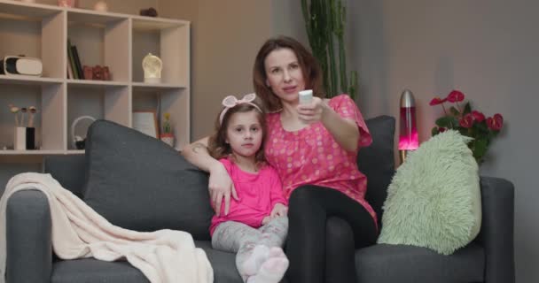 Woman with her daughter looking at TV and laughing. - Materiał filmowy, wideo