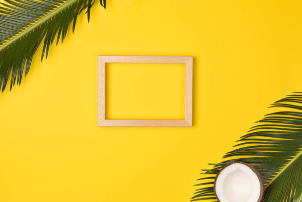 Palm leaves and photo frame, on yellow background. Top view, copy space. Flat lay. - Foto, immagini