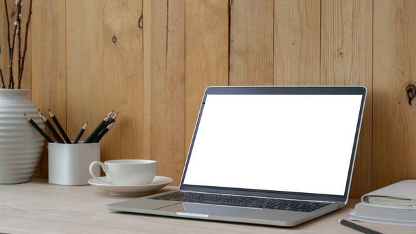 Oříznutý záběr současného pracovního prostoru s prázdnou obrazovkou notebook, kancelářské potřeby a dekorace na dřevěném stole s prknem stěny pozadí  - Fotografie, Obrázek