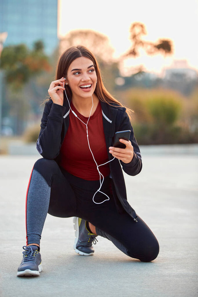 Modern young woman with cellphone making pause during jogging / exercise. - Fotoğraf, Görsel
