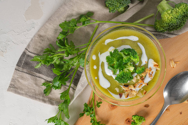 Készen áll, hogy friss brokkoli püré levest egyen brokkolival és petrezselyemlevéllel egy tálban egy fa asztalon. Közelkép. Egészséges táplálkozás és életmód. Felülnézet - Fotó, kép