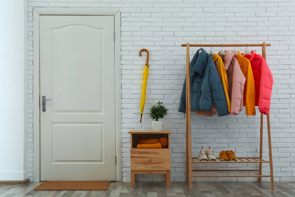 Wooden rack with stylish warm jackets in hallway - Фото, зображення