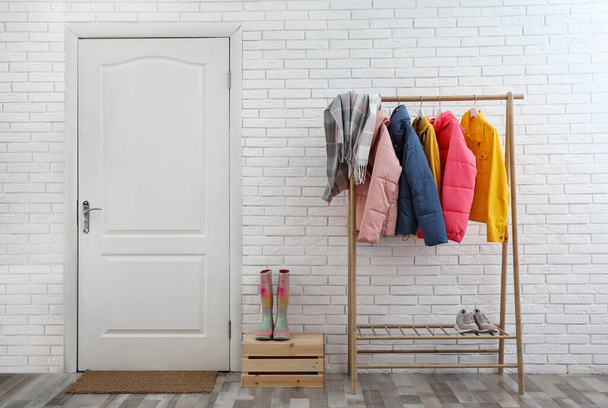 Wooden rack with stylish warm jackets in hallway - Foto, Imagen