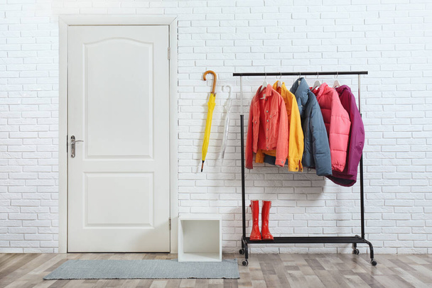 Rack with stylish warm jackets in hallway - Zdjęcie, obraz