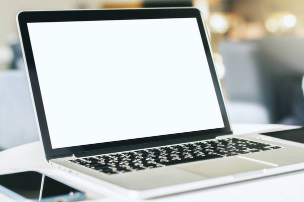 Zbliżenie nowoczesnego laptopa z czystym ekranem na białym stole w słonecznym wnętrzu, makieta. Koncepcja biznesu i technologii - Zdjęcie, obraz