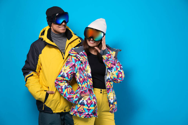 Couple wearing stylish winter sport clothes on light blue background - Valokuva, kuva