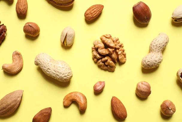 Different delicious nuts on yellow background, flat lay - Valokuva, kuva