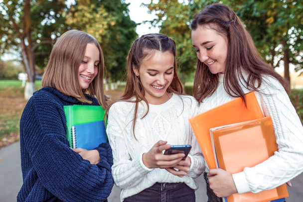 3 girls teenagers, smartphone. Holiday weekend, best friends, emotions happiness fun smile, folders textbooks. Rest school, college study. Happy smiling rejoices. Knowledge, education science. - Photo, Image