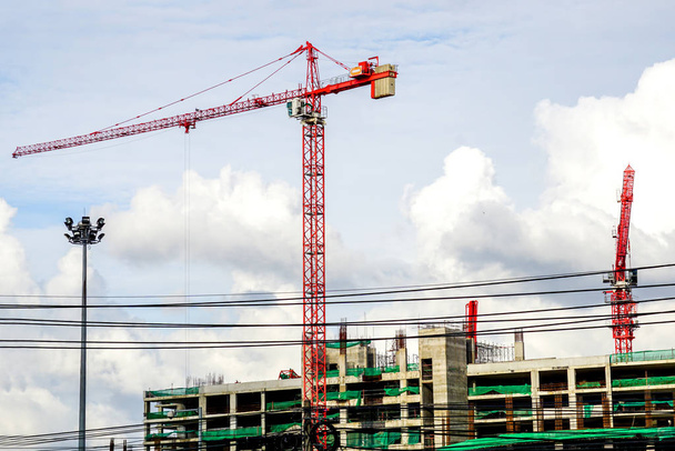 Emelő daruk dolgozó épület építése fényes kék ég és nagy felhő háttér. - Fotó, kép