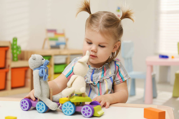 Malá holka si hraje s hračkami u stolu - Fotografie, Obrázek