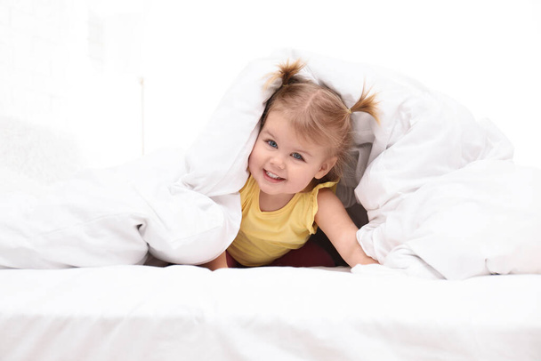 Cute little child playing under blanket in bed - Foto, Bild