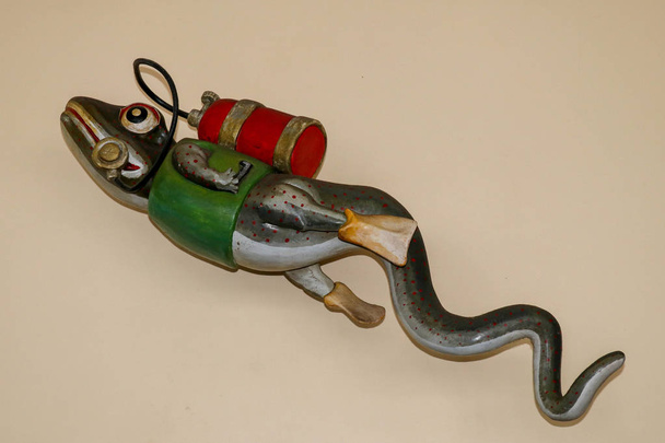 Estatua de gecko con equipo de buceo en la pared del centro de buceo. 3D gecko como buzo. Figura lagarto con chaqueta verde, tanque de buceo rojo y aletas amarillas. Un accesorio divertido en la base de buceo
. - Foto, Imagen
