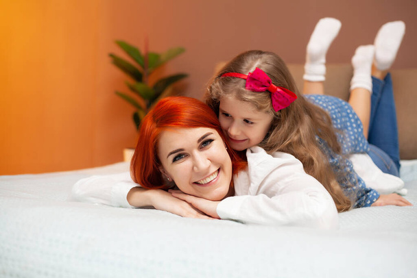 Mãe feliz e sua filha menina na cama no quarto
. - Foto, Imagem