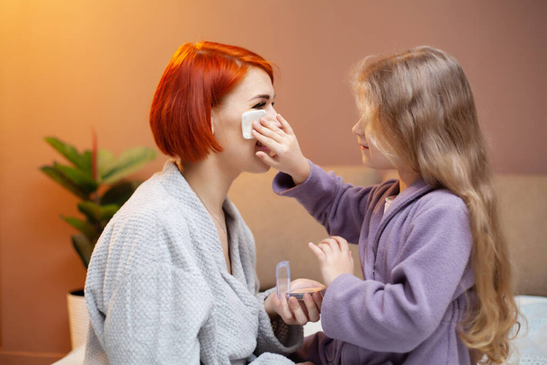 Daughter makes mom make up at home on bed. - Foto, afbeelding