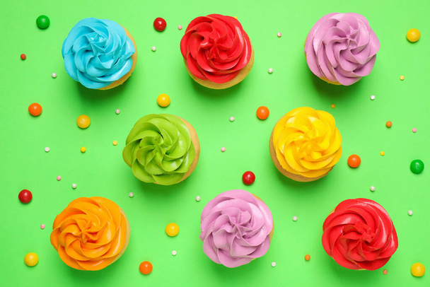 Colorful birthday cupcakes on green background, flat lay - 写真・画像