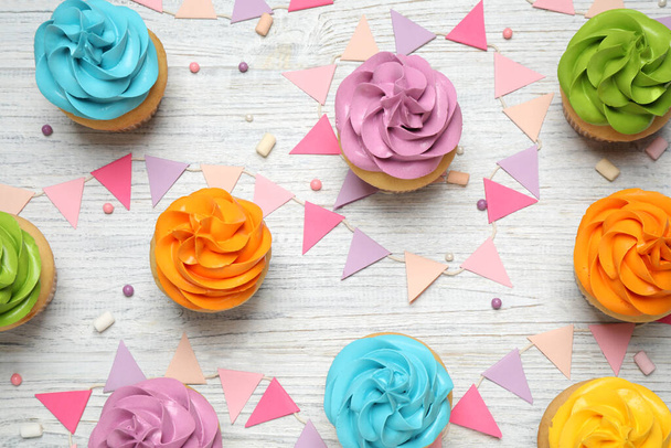 Colorful birthday cupcakes on white wooden table, flat lay - Foto, afbeelding