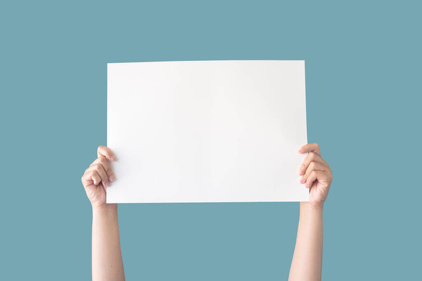 χέρι κρατώντας λευκό κενό χαρτί απομονωμένο σε μπλε φόντο με διαδρομή απόληξης - Φωτογραφία, εικόνα